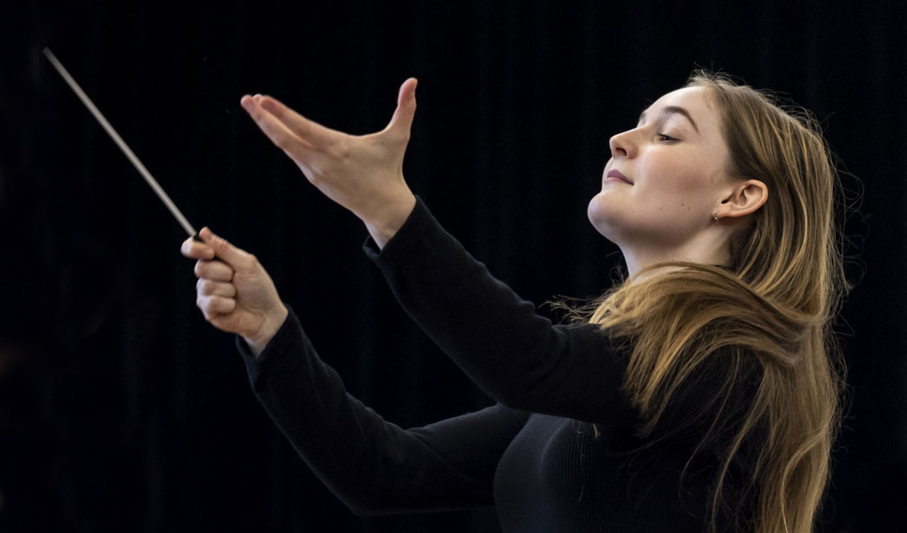 Alma Deutscher conducting, baton raised